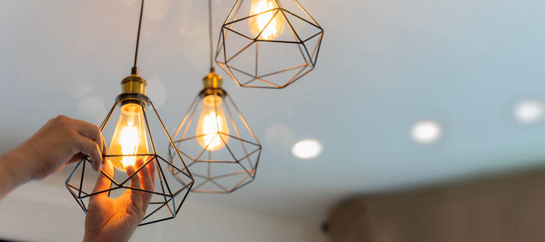 An electrician is installing spotlights on the ceiling.